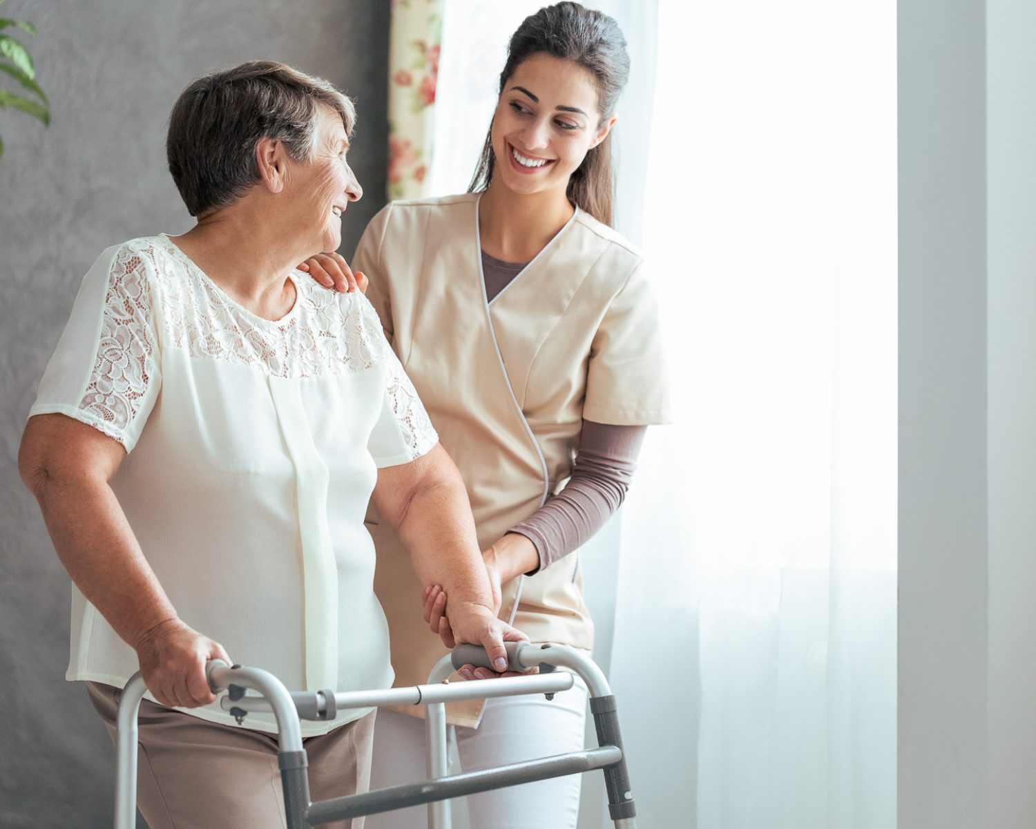 Smiling nurse helping senior lady to walk around the nursing home